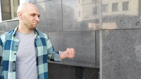 Angry young man hits the wall of building with his fist Video stock 201496414