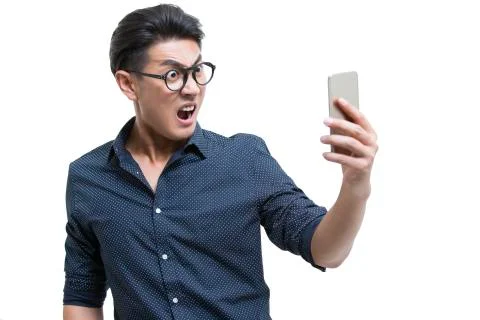 Angry young man looking at smart phone Stock Photos