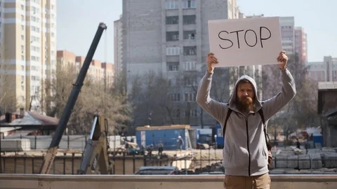 Angry young man protests with stop sign,near construction site.noise and debris Stock Footage 128954562