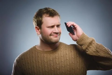 Angry young man talking on cell phone isolated on gray background Stock Photos