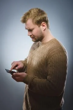 Angry young man talking on cell phone isolated on gray background Stock Photos