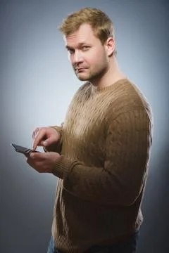 Angry young man talking on cell phone isolated on gray background Foto stock