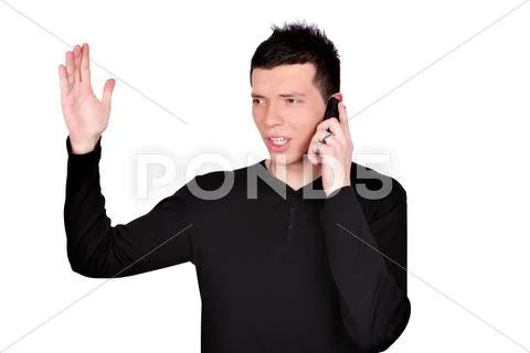 Angry young man talking on phone.JPG Stock Photos
