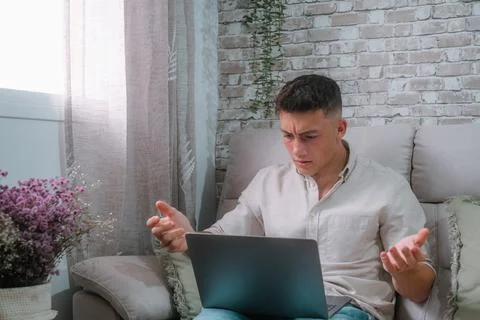 Angry young man using computer pc at home sitting on the sofa having problems Stock Photos