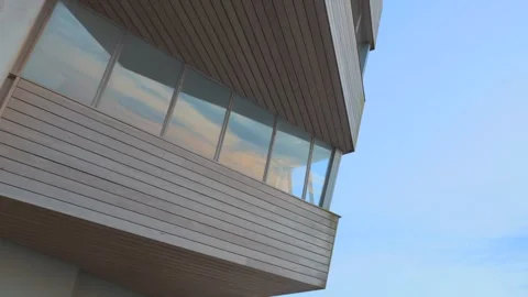 Angular building with cloud reflections in windows during sunset in slow Vídeos de archivo 243638754