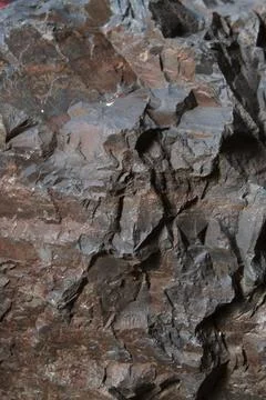 Angular dark brown rock texture with sharp deep fractures and solid blocky .. Stock Photos