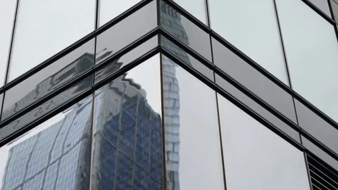 Angular glass facade of a modern office building capturing distorted reflections Vídeos de archivo 327531080