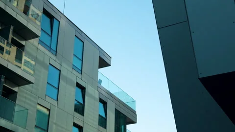Angular modern building with glass balconies against a clear sky. Vídeos de archivo 255629084