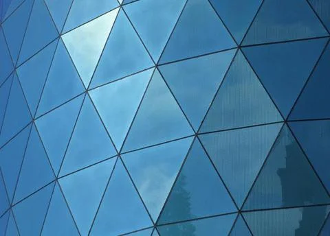  angular patterned mirrored windows panes reflecting the sky and clouds an... 스톡 사진