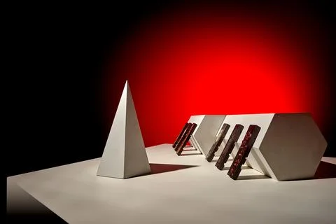 Angular prisms with chocolate bars in bold red and white studio composition Foto stock