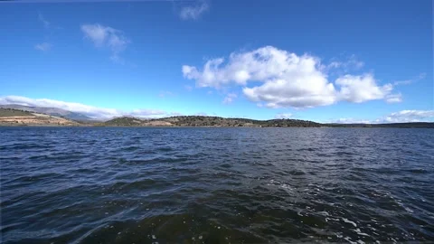 Angular view of blue lake with waves on windy day and white clouds in the sky Vídeos de archivo 172583094