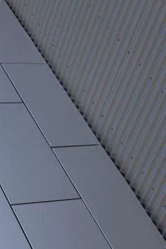 Angular view of corner of building - junction of grey smooth tiled wall and 스톡 사진