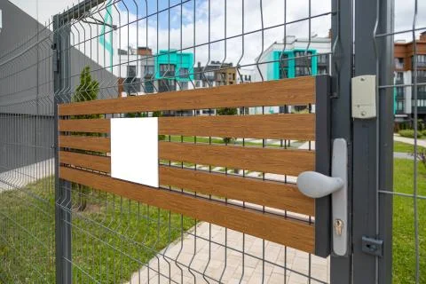 Angular view of metal gates with blank tablet on wooden planks Fotos de archivo