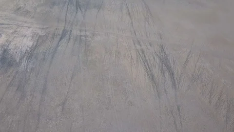 Animal tracks parallel to vehicle tracks on dry surface of salt pan aerial Stock Footage 80596872