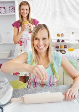 Animated female friends baking muffins smiling at the camera Stock Photos