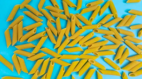 Animated raw pasta on a blue background, top view. Stop motion animation of a Stock Footage 144375177