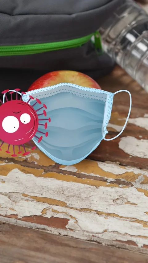 Animation of angry covid viruses bouncing against face mask over apple on school Stock Footage 342650937