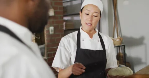 Animation of asian female baker explaining how to make a bread to her coworker Stock Footage 341936325