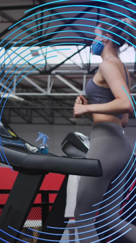 Animation of blue spiral rotating over women in face masks exercising on running Stock Footage 324610946