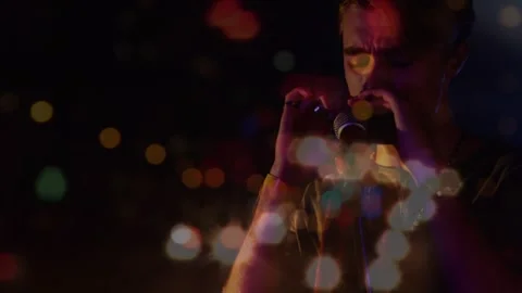Animation of blurred night road traffic over caucasian man playing harmonica on Video stock 328645294