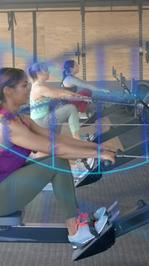 Animation of dna strands over diverse women training on rowing machines at gym Stock Footage 323783009