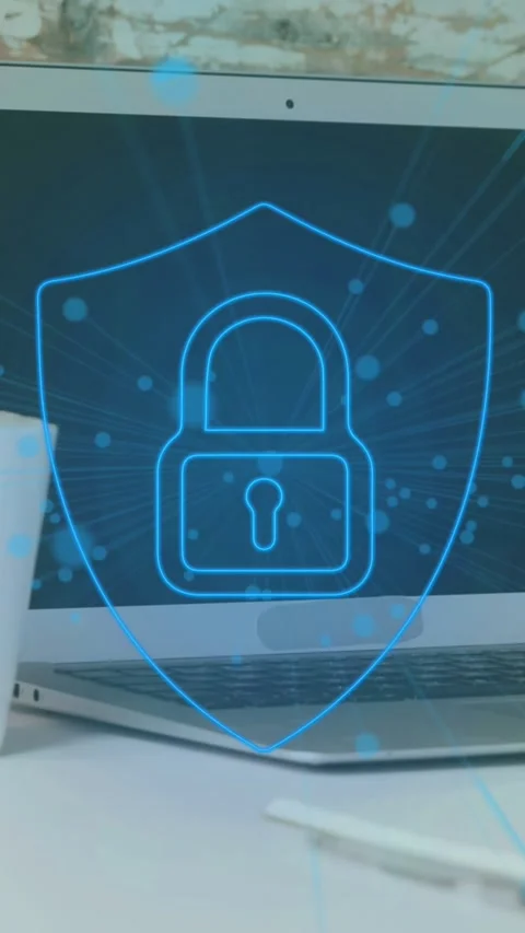 Animation of dots around padlock in shield over coffee cup and laptop on desk at Stock Footage 344636186