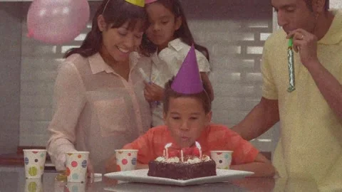 Animation of falling balloons, boy blowing candles on cake and family whistling Stock Footage 325774173