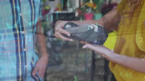 Animation of financial data processing over caucasian woman paying at payment Stock Footage 220378663