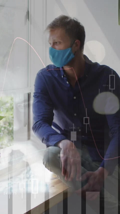 Animation of financial graphs over caucasian man in face mask sitting at window Stock Footage 322954150