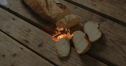 Animation of fire overlay under sliced bread on wooden surface Video stock 305117752