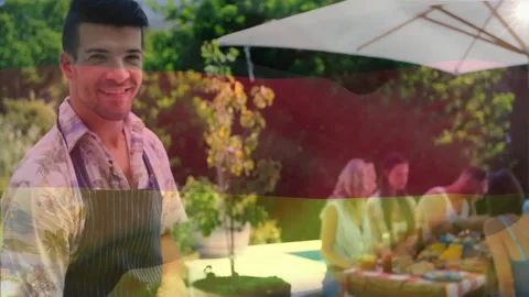 Animation of flag of germany waving over man with drink cooking food on barbeque Stock Footage 330175428