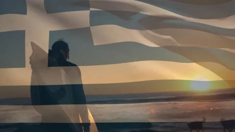 Animation of flag of greece over caucasian man with surfboard on beach Stock Footage 310530403