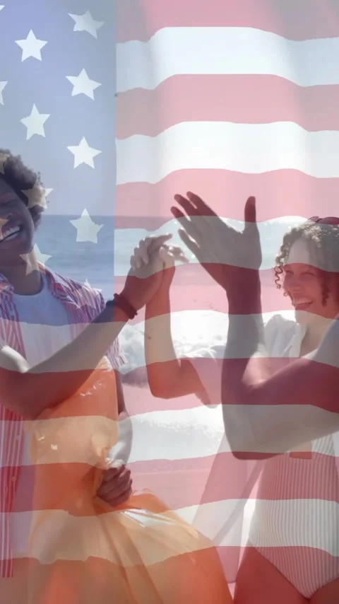 Animation of flag of usa over diverse friends high fiving on beach Stock Footage 343079139