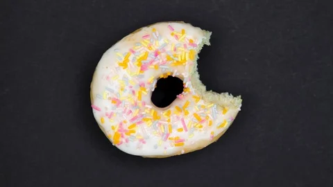 Animation with glazed donut on dark grey background. Eating bite by bite Stock Footage 128922872