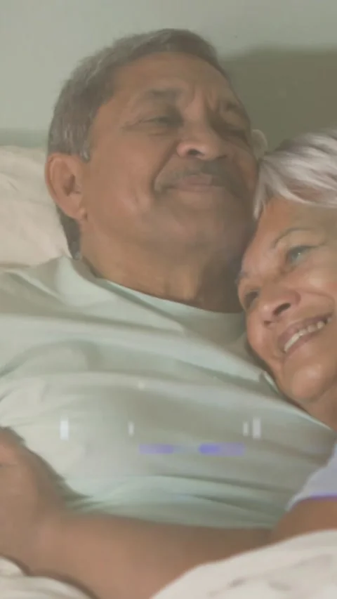Animation of glowing lights over happy senior couple lying in bed in background Vídeo Stock 342097434