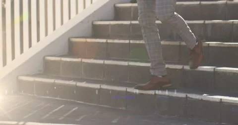 Animation of glowing lights over low section of businessman walking down steps Stock Footage 172363264