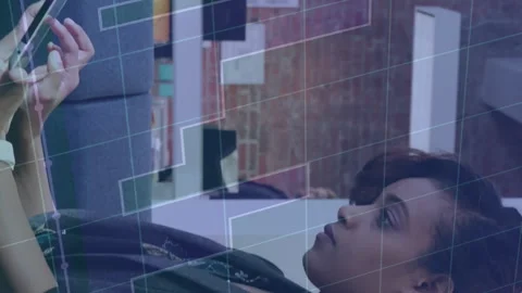 Animation of graph and grid pattern over woman scrolling on digital tablet in 스톡 동영상 312288754