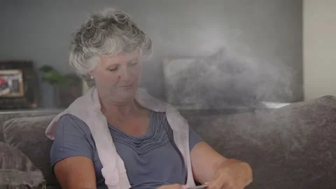 Animation of grey smoke over senior caucasian woman knitting Stockbeeldmateriaal 325699720