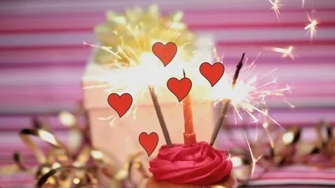 Animation of hearts falling over candle and fireworks on cupcake Stock Footage 316584496