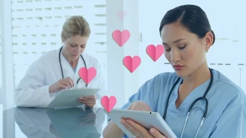 Animation of hearts floating over diverse female doctors making notes Stock Footage 328009739