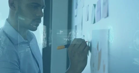 Animation of infographic interface, dna helix over african american man writing Stock Footage 327584503