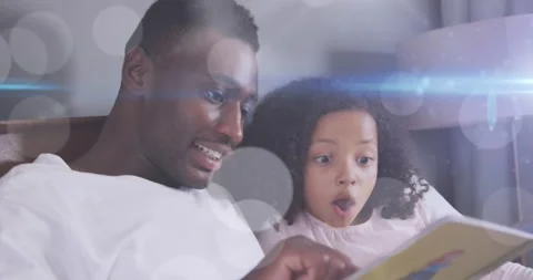 Animation of light spots over happy african american father reading book with Stock Footage