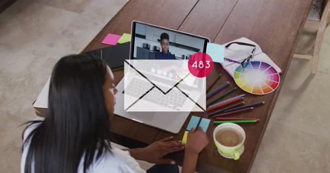 Animation of mail icon and numbers over biracial businesswoman using laptop Stock Footage 235393103