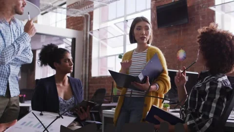 Animation of math text banner over team of diverse colleagues discussing Stock Footage 327274648