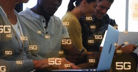 Animation of multiple 5g texts over diverse coworkers working and using laptop Stock Footage 253471684