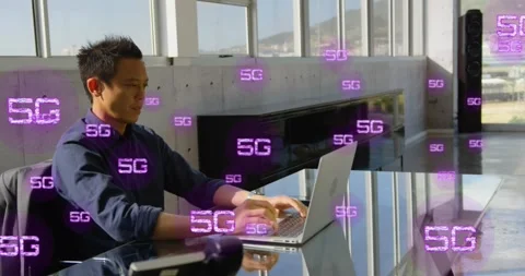 Animation of multiple 5g texts over asian man sitting on chair and working on Stock Footage 328087780