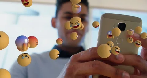 Animation of multiple face emojis floating over man using smartphone at office Stock Footage 329987897