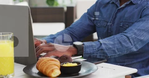 Animation of multiple icons and graphs over biracial man working on laptop in Stock Footage 253989935