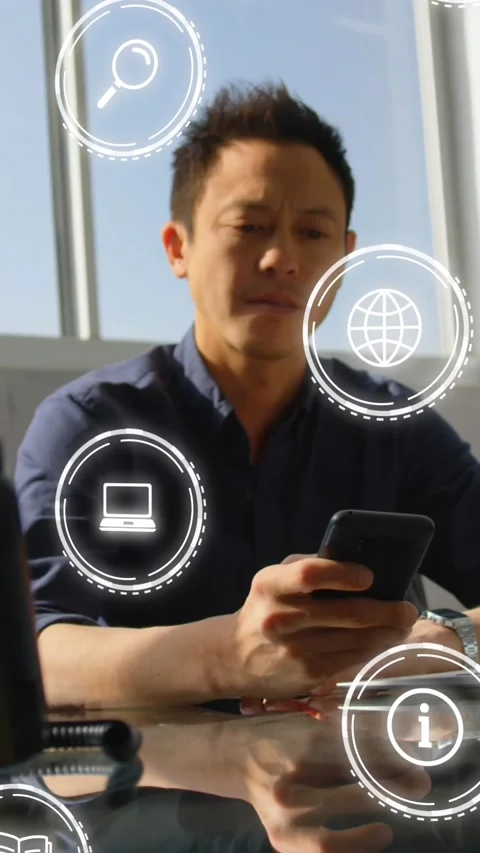 Animation of multiple icons over asian man sitting on chair and scrolling on Stock Footage 320811591