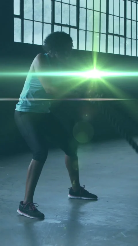 Animation of shining light floating over woman exercising with ropes in an Stock Footage 320165387